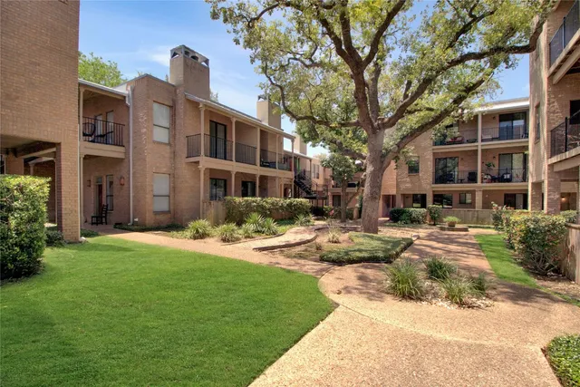a front view of a building with garden and trees