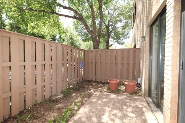 a view of a backyard with wooden fence and a bench