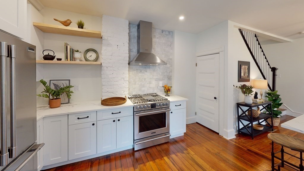 a kitchen with stainless steel appliances a stove a white cabinets and wooden floor