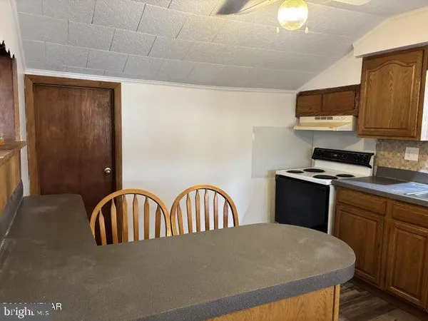 a kitchen with stainless steel appliances granite countertop a table chairs a refrigerator a sink and dishwasher