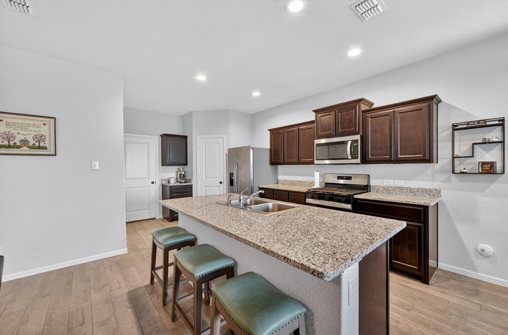 9604 Cherryville Road Fort Worth, TX 76108 - Photo 10 of 40 Kitchen featuring wood-finish flooring, dark wood cabinetry, and speckled light countertops