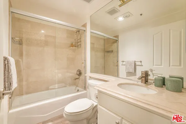 a bathroom with a granite countertop sink a toilet and shower