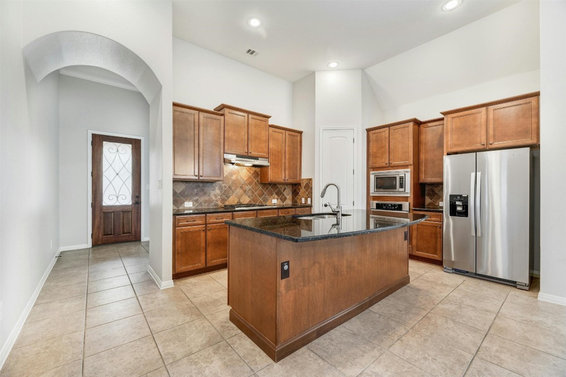 a kitchen with stainless steel appliances granite countertop a refrigerator and a stove