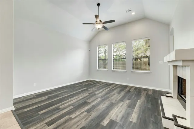 a view of an empty room with wooden floor fireplace and a window