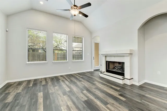 a view of an empty room with wooden floor fireplace and a window