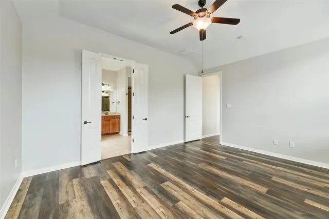 a view of empty room with wooden floor and ceiling fan