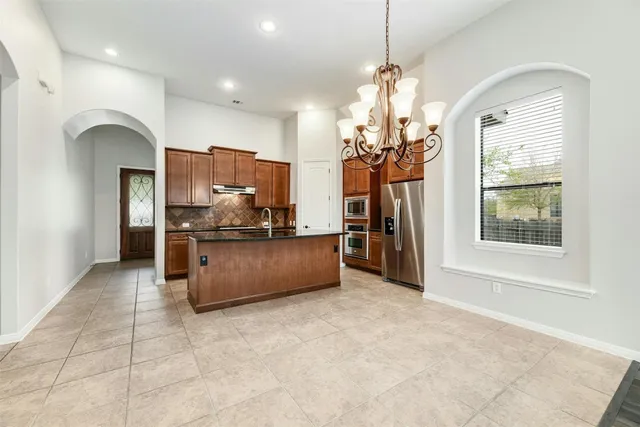 a large kitchen with stainless steel appliances granite countertop a stove a sink a refrigerator and a cabinets
