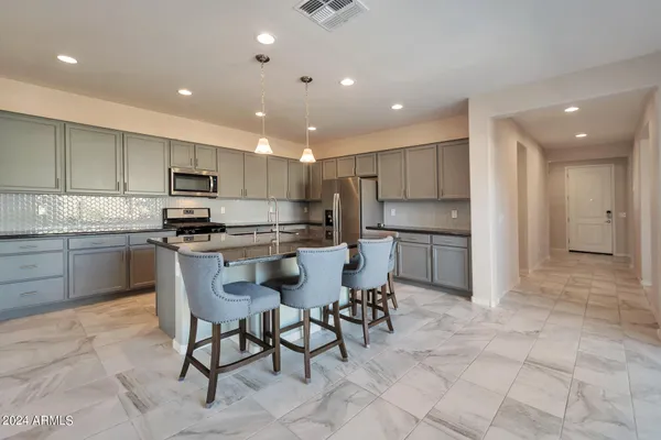 a kitchen with kitchen island granite countertop stainless steel appliances a sink a counter top space appliances and cabinets