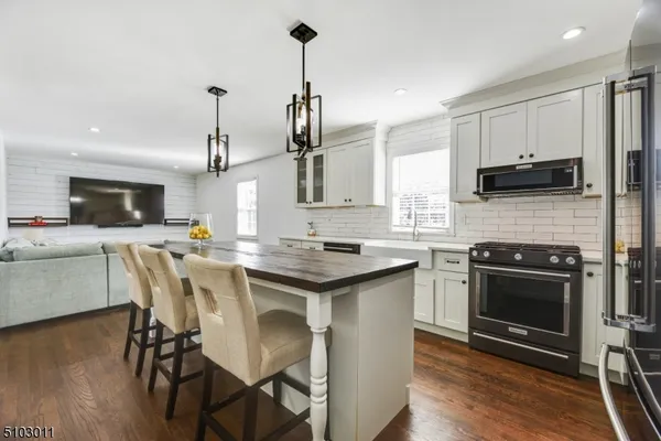 a kitchen with stainless steel appliances kitchen island granite countertop a stove top oven a sink a dining table and chairs with wooden floor