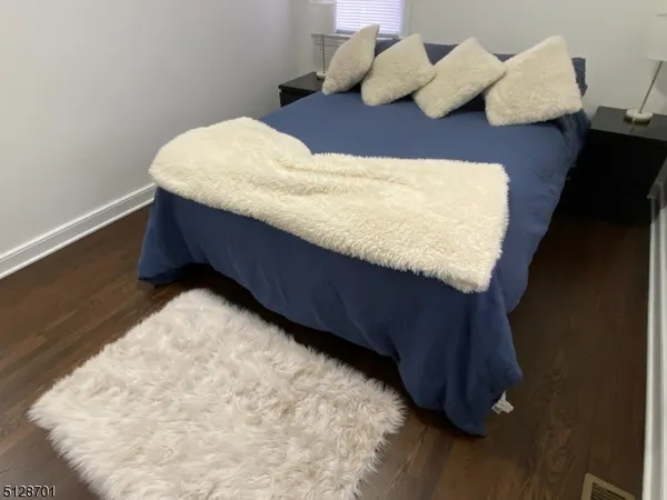a bed sitting in a bedroom next to a window with wooden floor