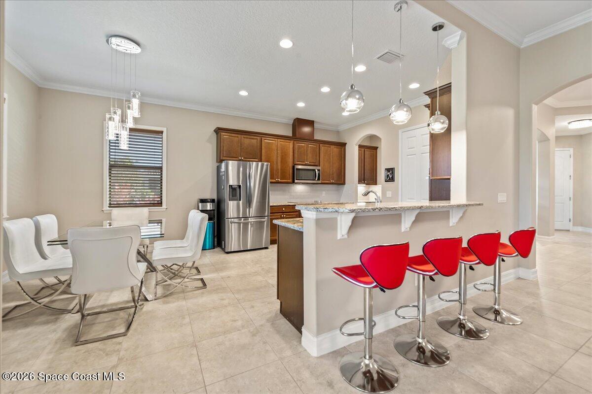 2906 Balting Place Melbourne, FL 32940 - Photo 16 of 44 a kitchen with stainless steel appliances kitchen island granite countertop a dining table chairs sink and white cabinets