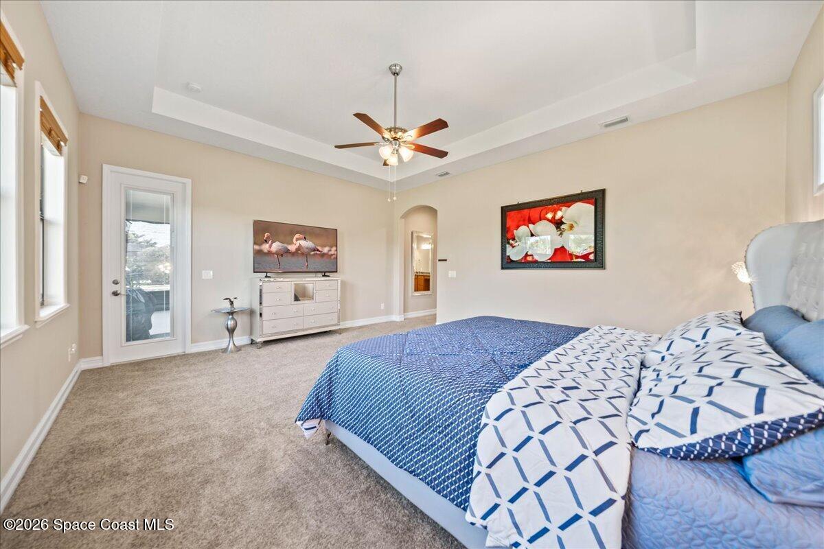 2906 Balting Place Melbourne, FL 32940 - Photo 23 of 44 a bedroom with a large bed a chandelier and dresser