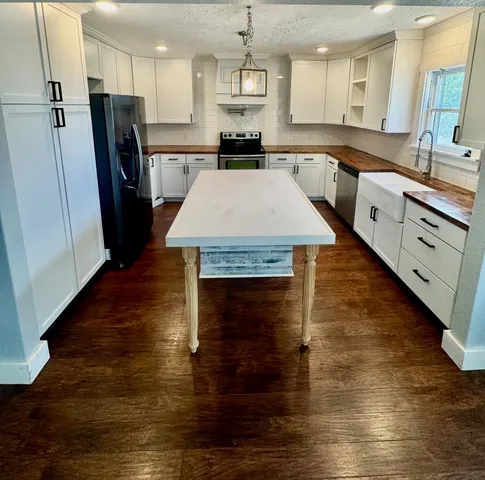 a large kitchen with stainless steel appliances granite countertop a refrigerator a stove and a wooden floors