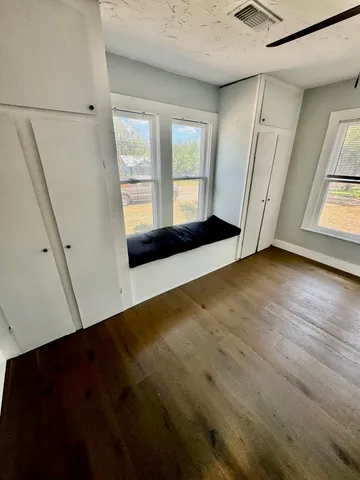 a view of an empty room with a window and wooden floor