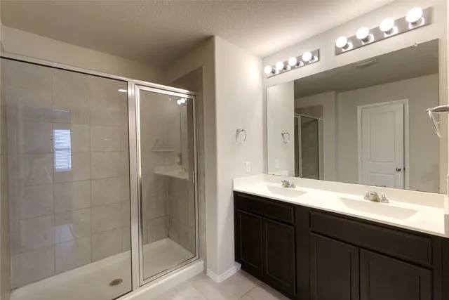 a bathroom with a bathtub shower sink vanity and mirror