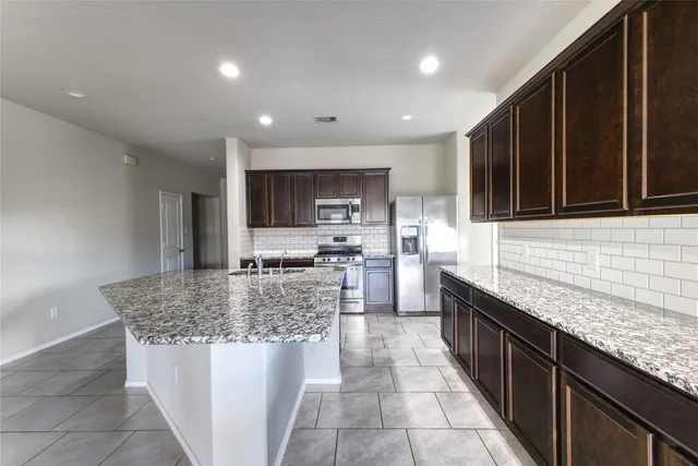 a kitchen with stainless steel appliances granite countertop a stove top oven a sink dishwasher a dining table and chairs