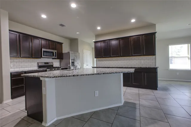 a kitchen with stainless steel appliances granite countertop a stove a sink and a microwave