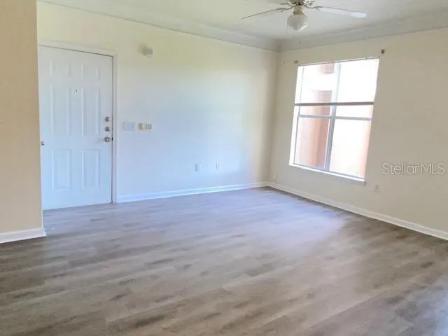 an empty room with wooden floor and windows