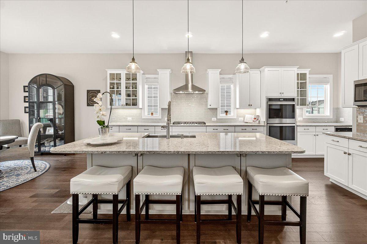 5487 Tallyn Ridge Drive Frederick, MD 21704 - Photo 8 of 80 a kitchen with stainless steel appliances kitchen island granite countertop a table chairs and a wooden cabinets