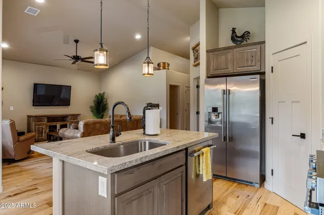 a kitchen with stainless steel appliances granite countertop a stove a sink dishwasher and a refrigerator with wooden floor