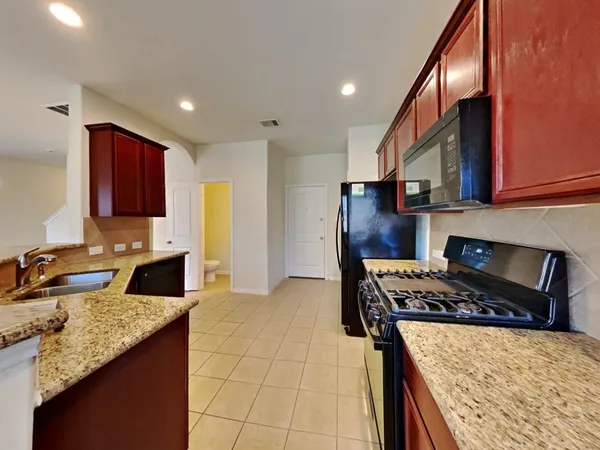 a kitchen with stainless steel appliances granite countertop a stove a sink and a microwave