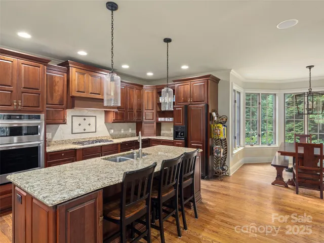 a kitchen with stainless steel appliances granite countertop a kitchen island a stove a table and chairs