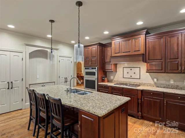 a kitchen with granite countertop kitchen island stainless steel appliances a sink and wooden cabinets