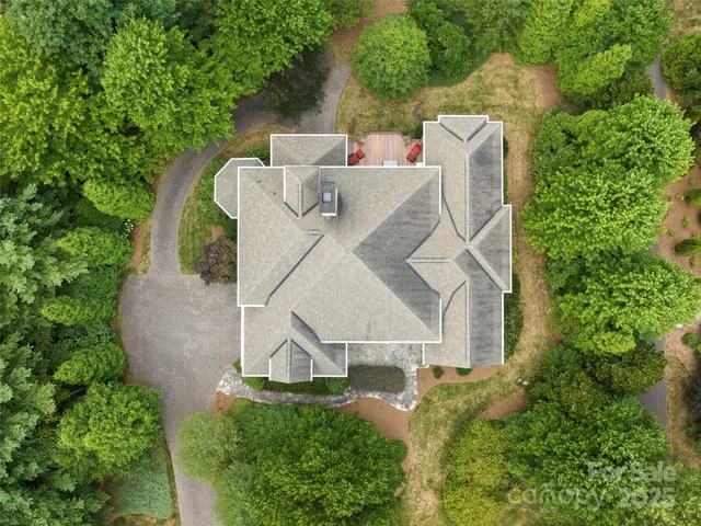 an aerial view of a house with outdoor space and trees all around