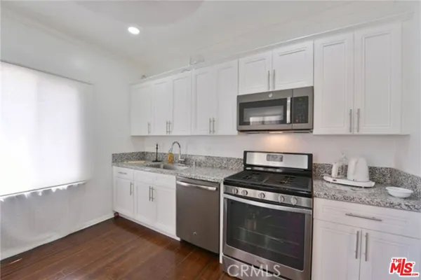 a kitchen with granite countertop white cabinets and black appliances