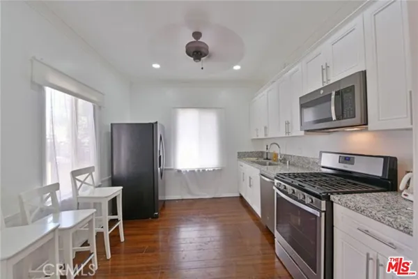 a kitchen with granite countertop kitchen island stainless steel appliances a stove a sink a refrigerator cabinets and a window