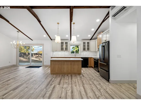 a kitchen with stainless steel appliances granite countertop a refrigerator a sink dishwasher a stove and white countertops with wooden floor