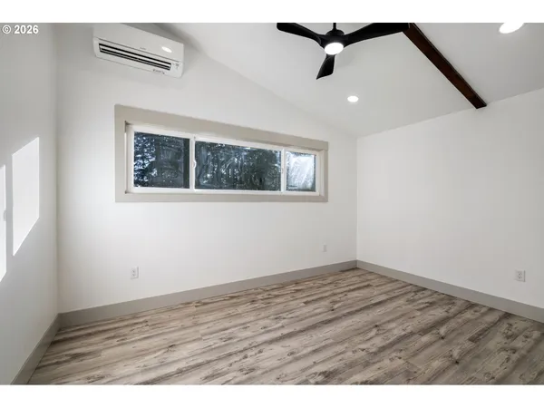 an empty room with wooden floor ceiling fan and windows