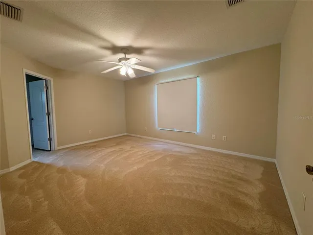 an empty room with a chandelier fan and windows