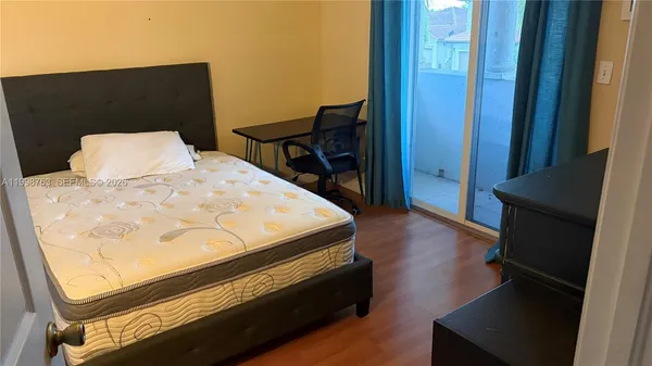 a bed sitting in a bedroom next to a window with wooden floor