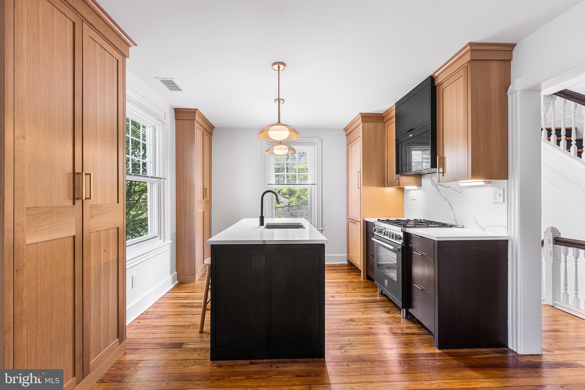 a kitchen with stainless steel appliances granite countertop a refrigerator a sink dishwasher a oven and a dining table with wooden floor