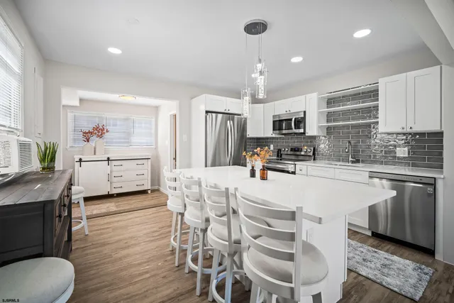 a kitchen with stainless steel appliances a stove a sink a oven a dining table and chairs