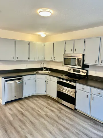 a kitchen with stainless steel appliances granite countertop a stove a sink and white cabinets