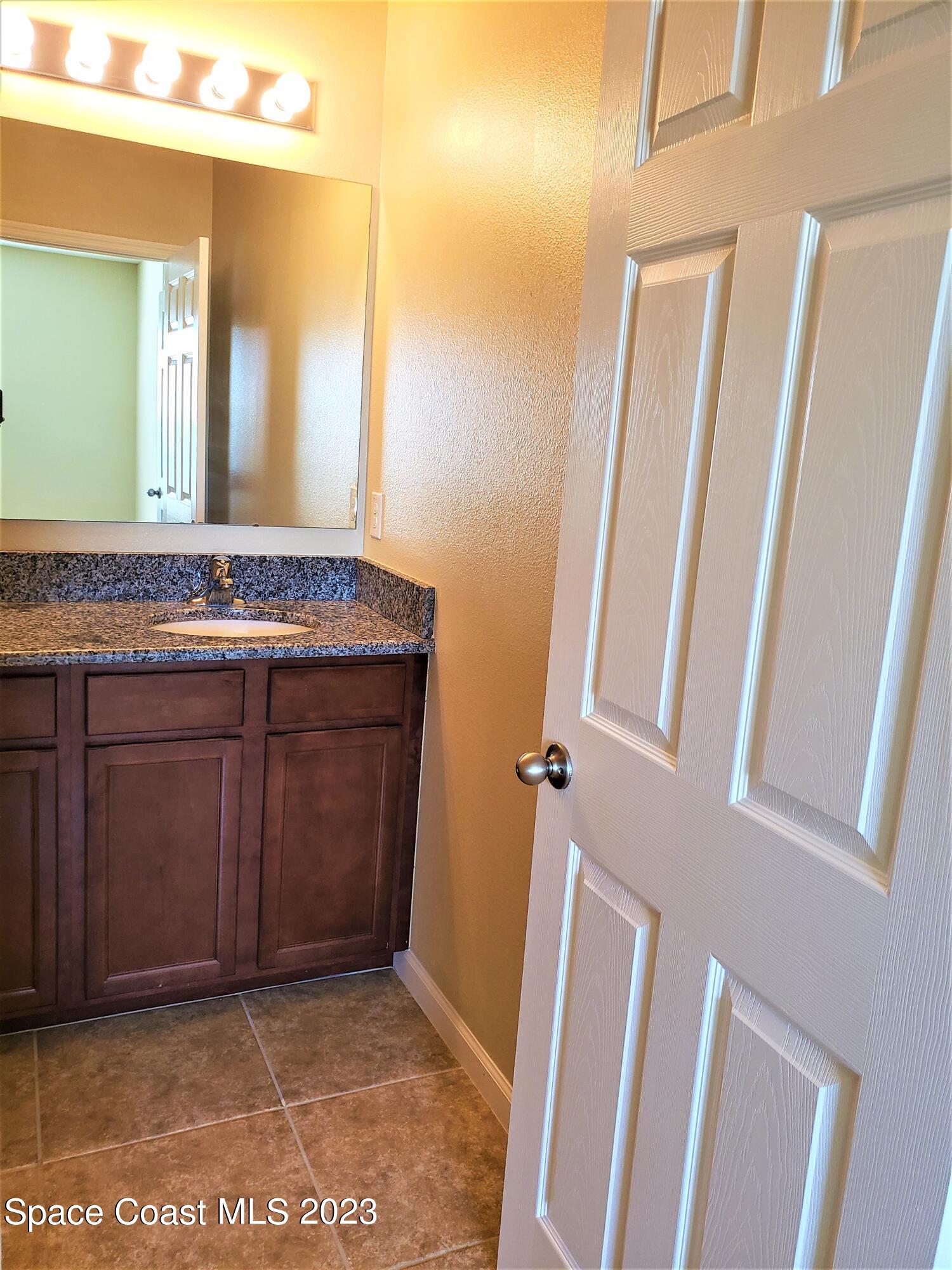 2575 Revolution Street, Unit 105 Melbourne, FL 32935 - Photo 14 of 38 a bathroom with a granite countertop sink and a mirror