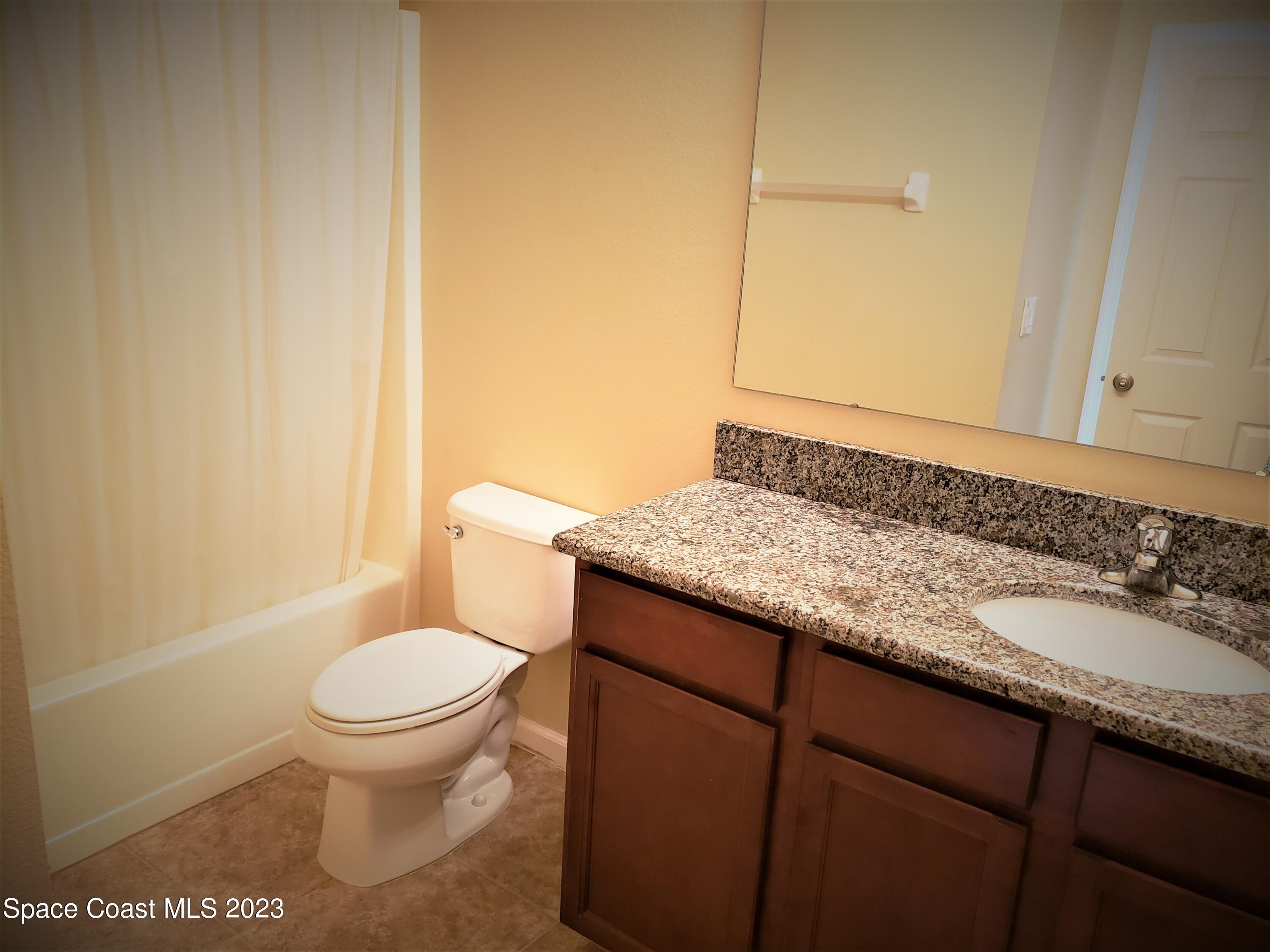 2575 Revolution Street, Unit 105 Melbourne, FL 32935 - Photo 15 of 38 a bathroom with a granite countertop toilet and sink