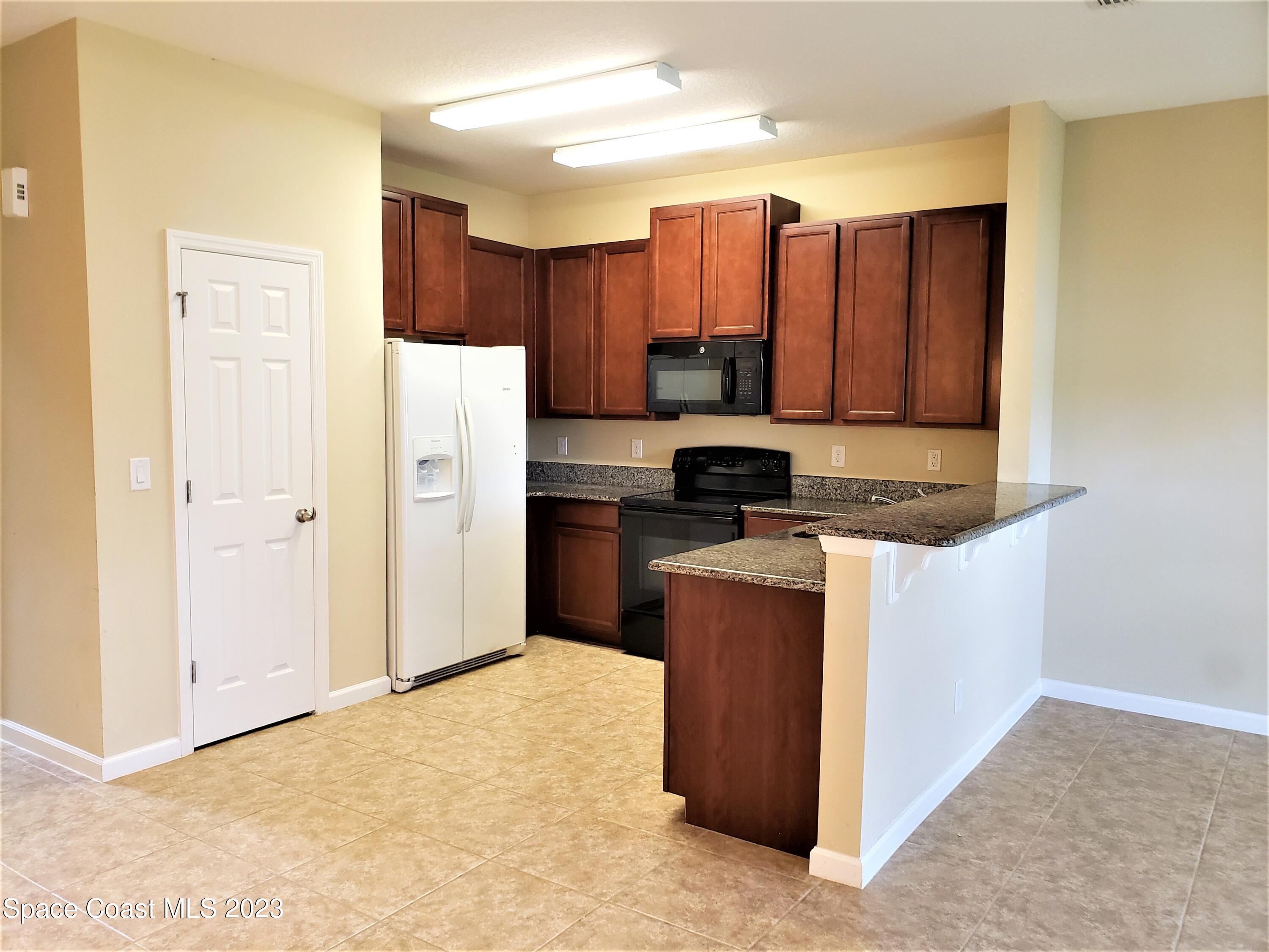 2575 Revolution Street, Unit 105 Melbourne, FL 32935 - Photo 6 of 38 a kitchen with stainless steel appliances granite countertop a refrigerator and a sink