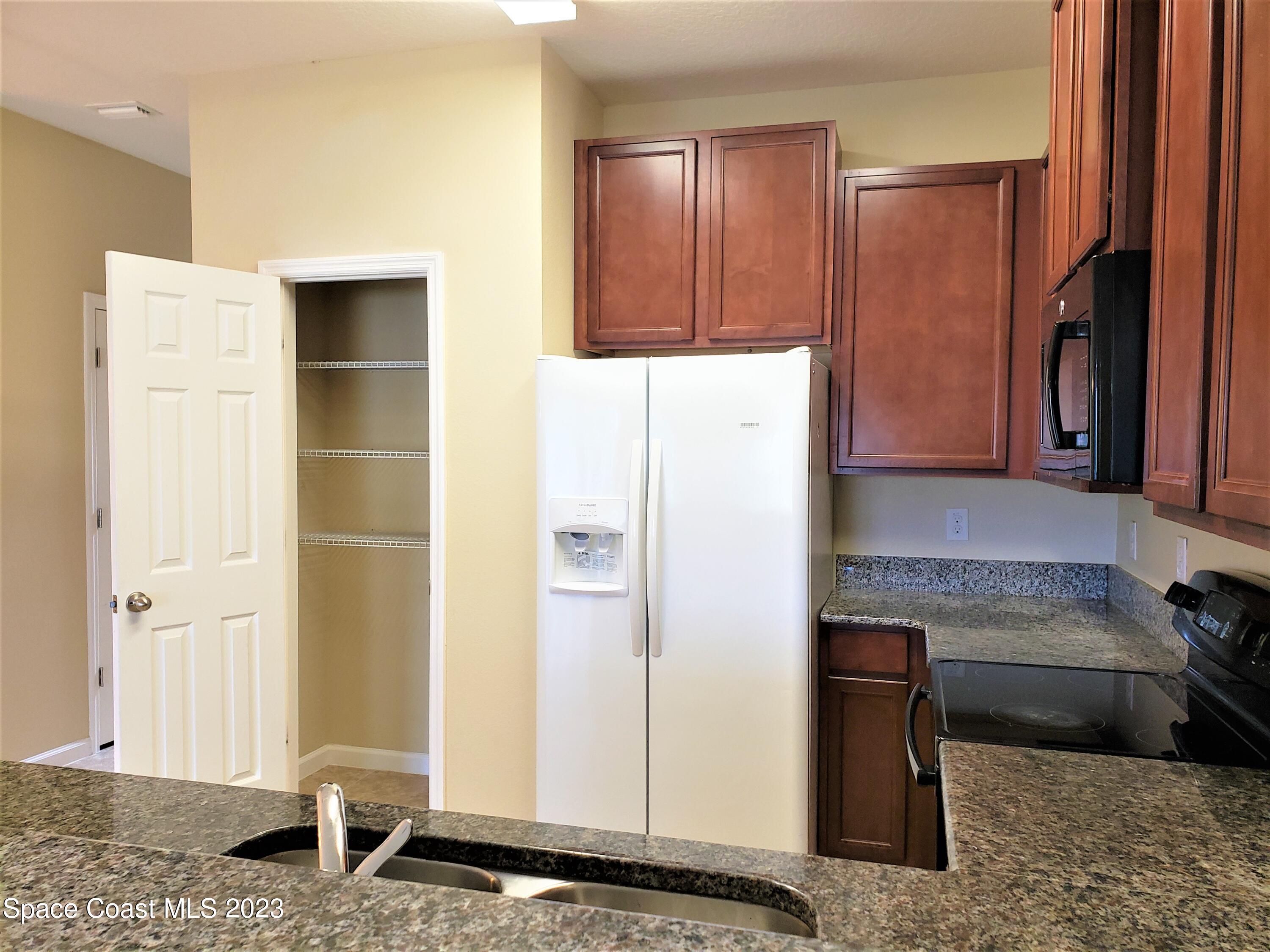 2575 Revolution Street, Unit 105 Melbourne, FL 32935 - Photo 7 of 38 a kitchen with stainless steel appliances granite countertop a refrigerator and a stove