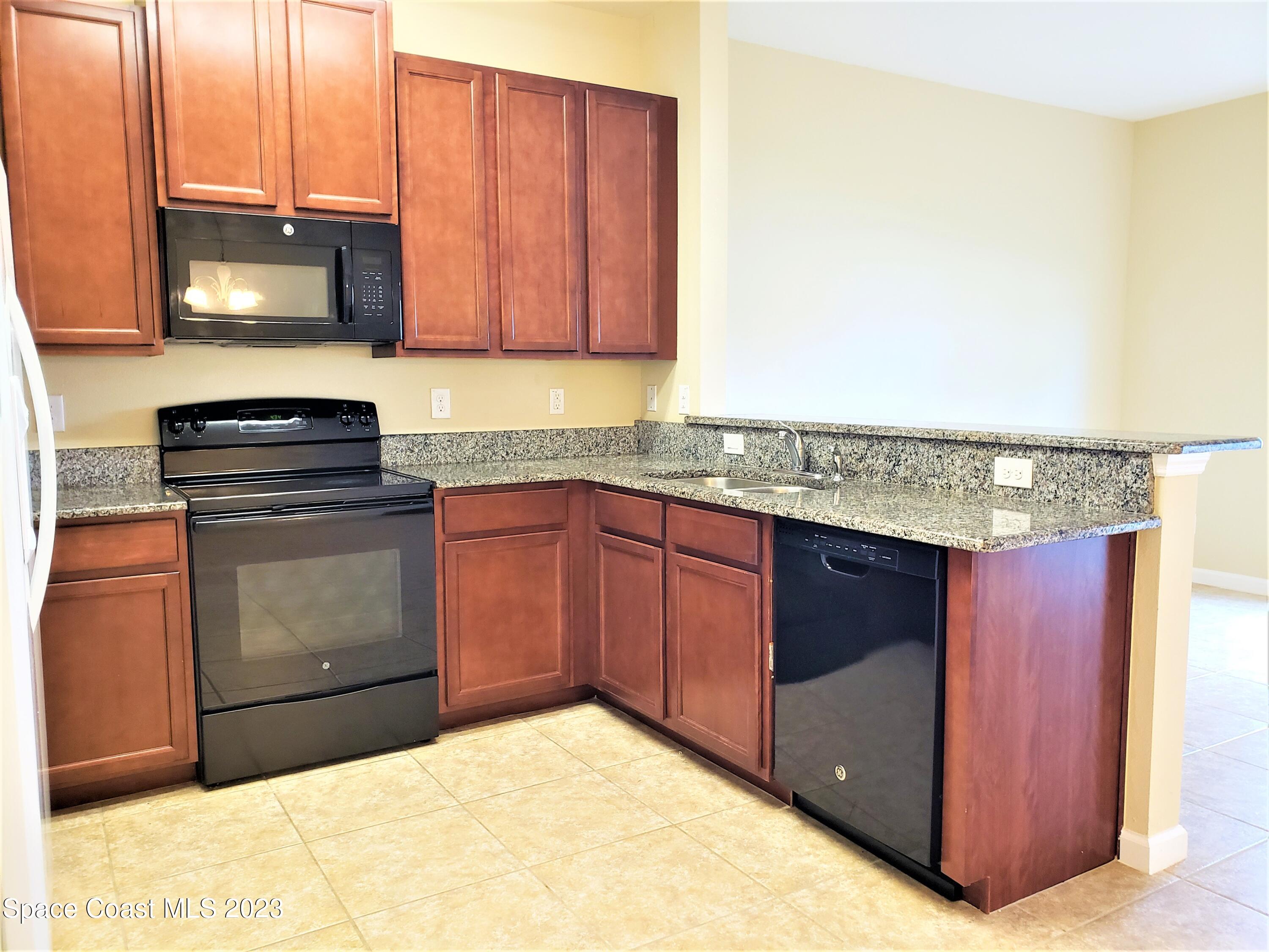 2575 Revolution Street, Unit 105 Melbourne, FL 32935 - Photo 8 of 38 a kitchen with stainless steel appliances granite countertop a stove a sink and a microwave