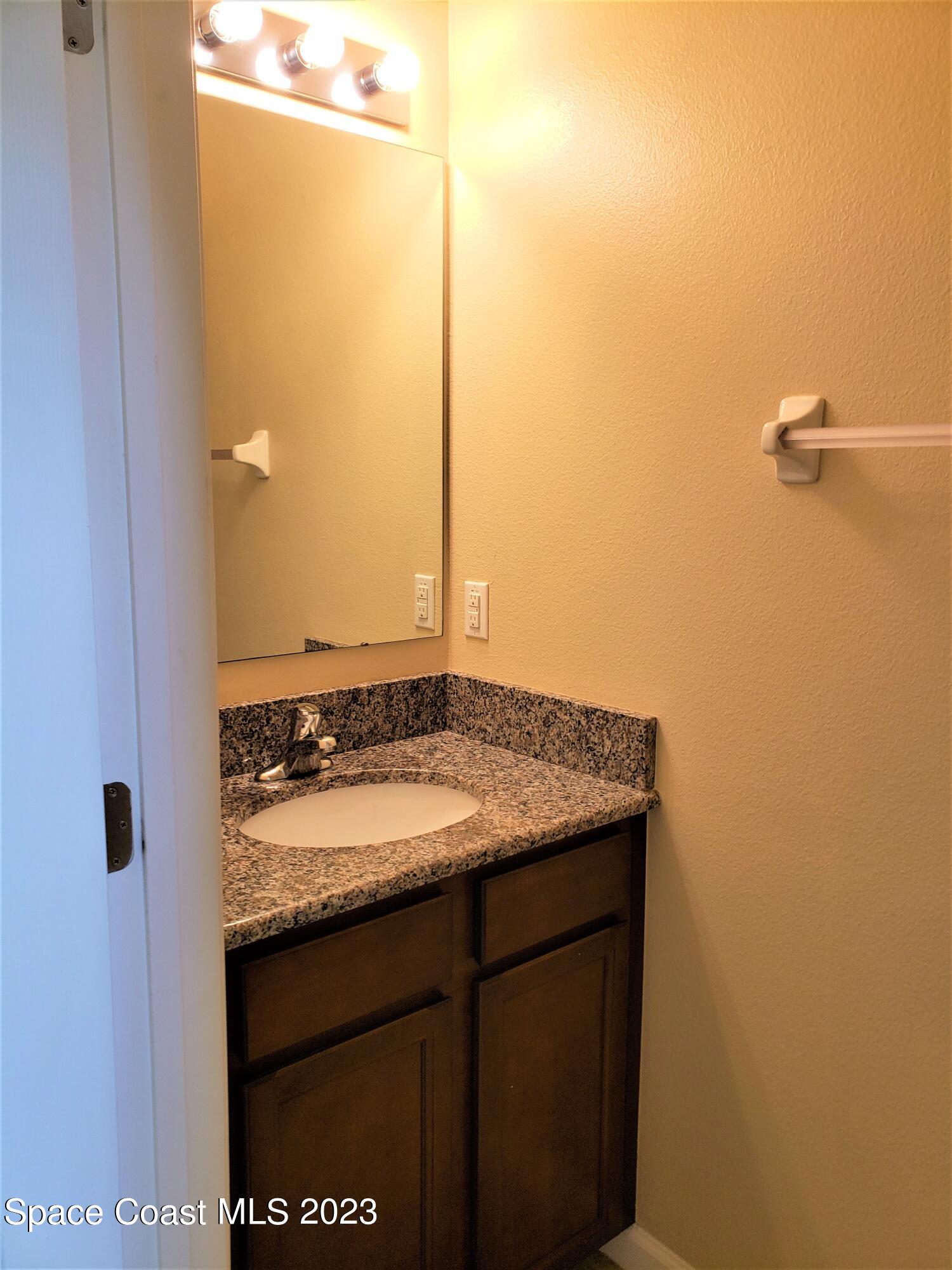 2575 Revolution Street, Unit 105 Melbourne, FL 32935 - Photo 9 of 38 a bathroom with a granite countertop sink and a mirror