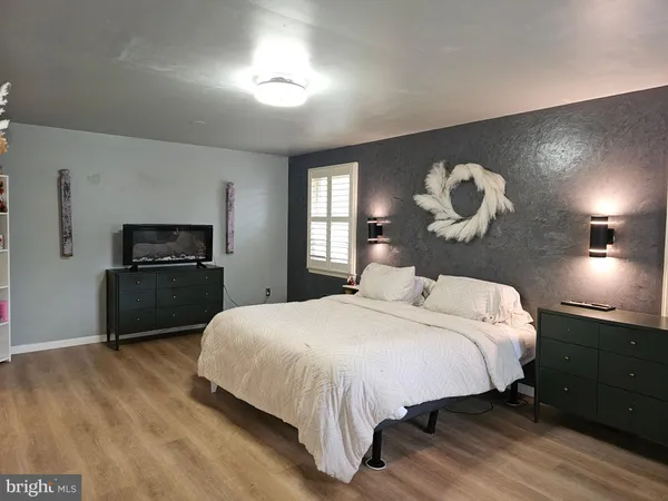 a bedroom with a bed and a flat tv screen on dresser