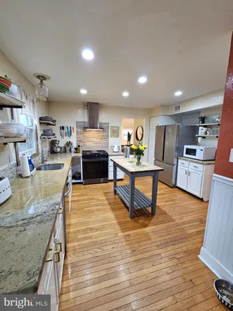 a kitchen with stainless steel appliances granite countertop wooden cabinets a sink dishwasher and a stove with wooden floor