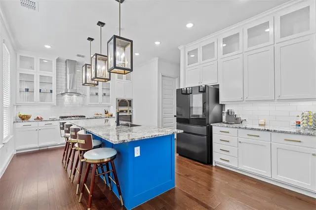 a kitchen with stainless steel appliances kitchen island granite countertop a sink refrigerator and cabinets