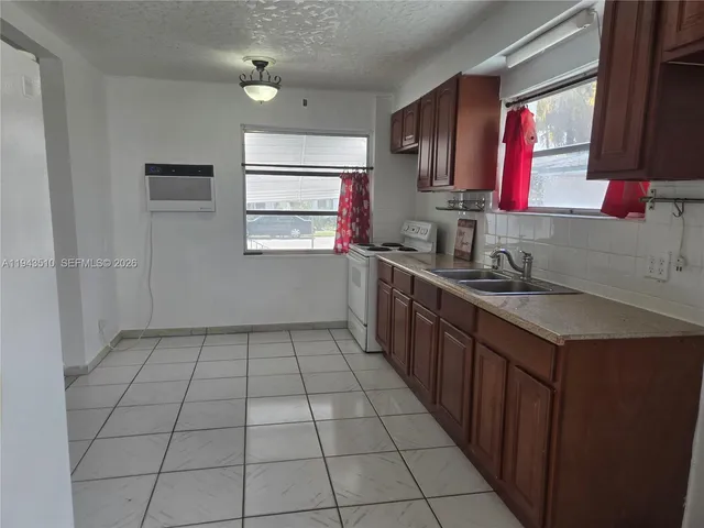 a kitchen with a sink a stove cabinets and a window