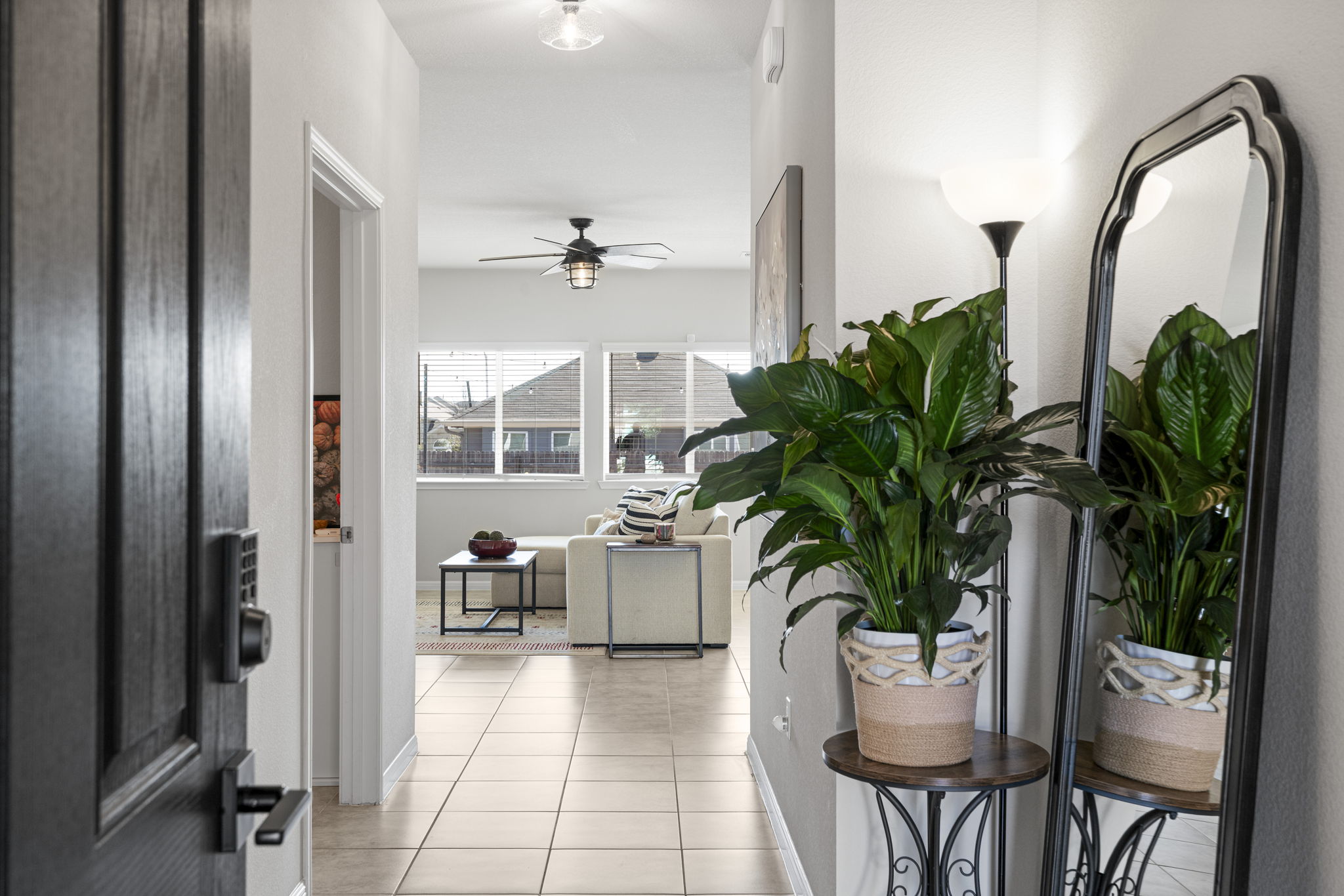 a hallway with a potted plant on a table and chairs