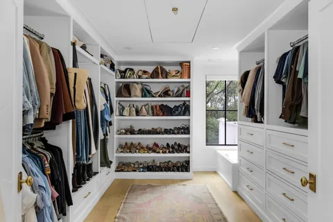 a view of walk in closet with clothes and shoes
