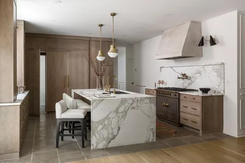 a kitchen with stainless steel appliances kitchen island granite countertop a sink a stove and a wooden floors